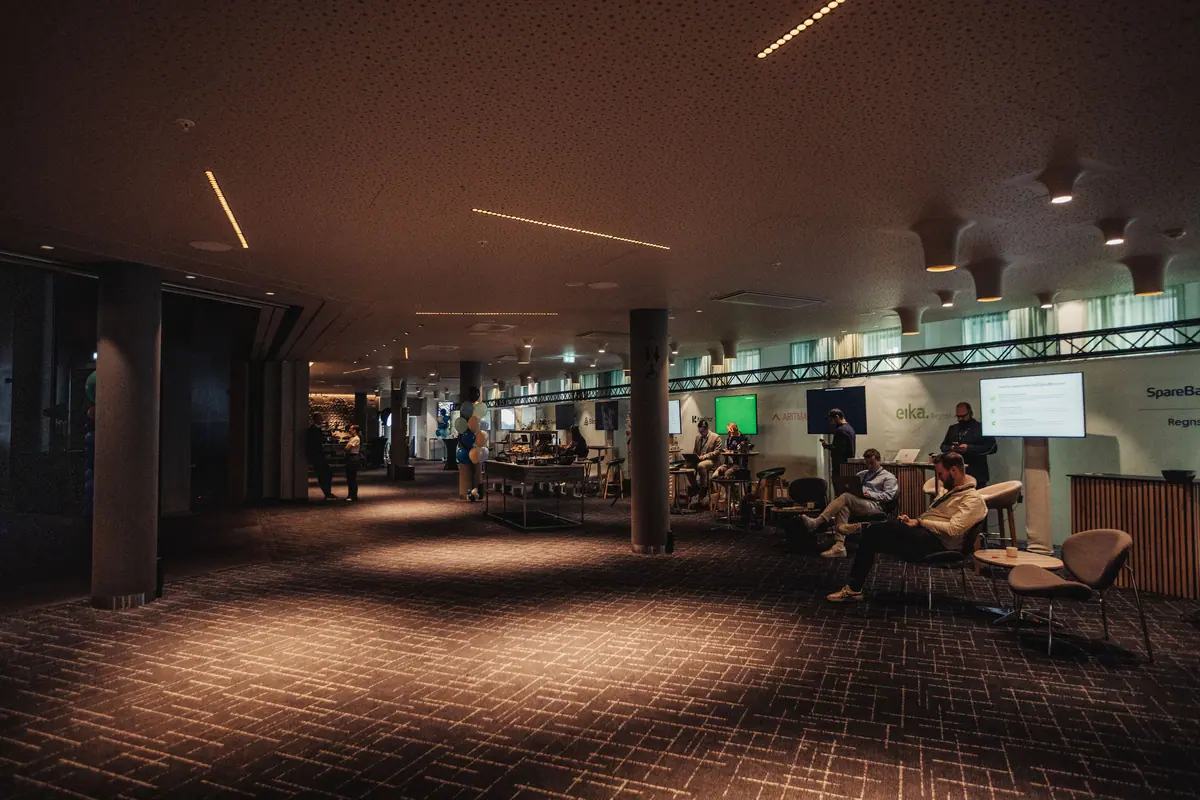 Dempet opplyst expo-område med sittegrupper og skjermer