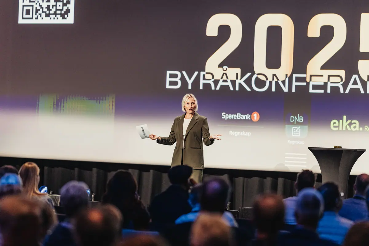 Foredragsholder på scenen foran skjerm med «Byråkonferansen 2025» og partnerlogoer