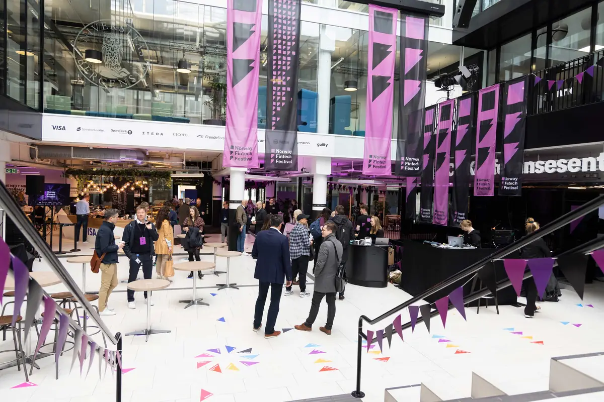 Deltakere mingler i atriet i Media City Bergen pyntet med Norway Fintech Festival-bannere
