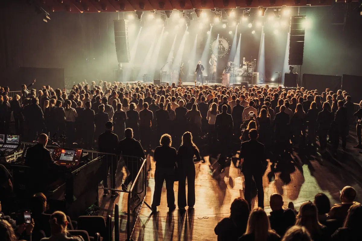 Konsertpublikum sett bakfra mot en scene med lysrigg og røyk