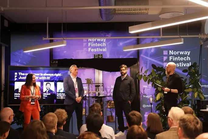 Fire personer på en liten scene foran Norway Fintech Festival-skjermer