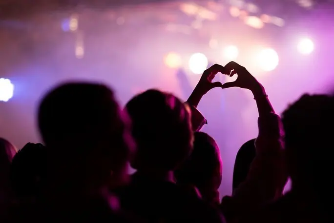 Silhuetter av publikum som former hjerte med hendene under konsert